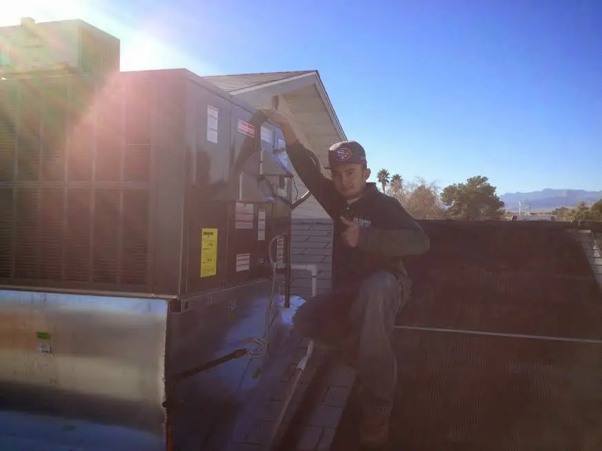 HVAC technician performing Air Duct Cleaning on a rooftop unit in Emporia